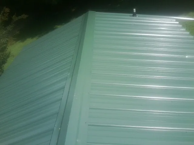 New green metal panels meeting at the ridge of a roof — Flat Roof Repair work by our crew in Tamworth