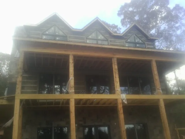 Dormers and porch framing on a large log home under construction — Roof Coating work by our crew in Tamworth
