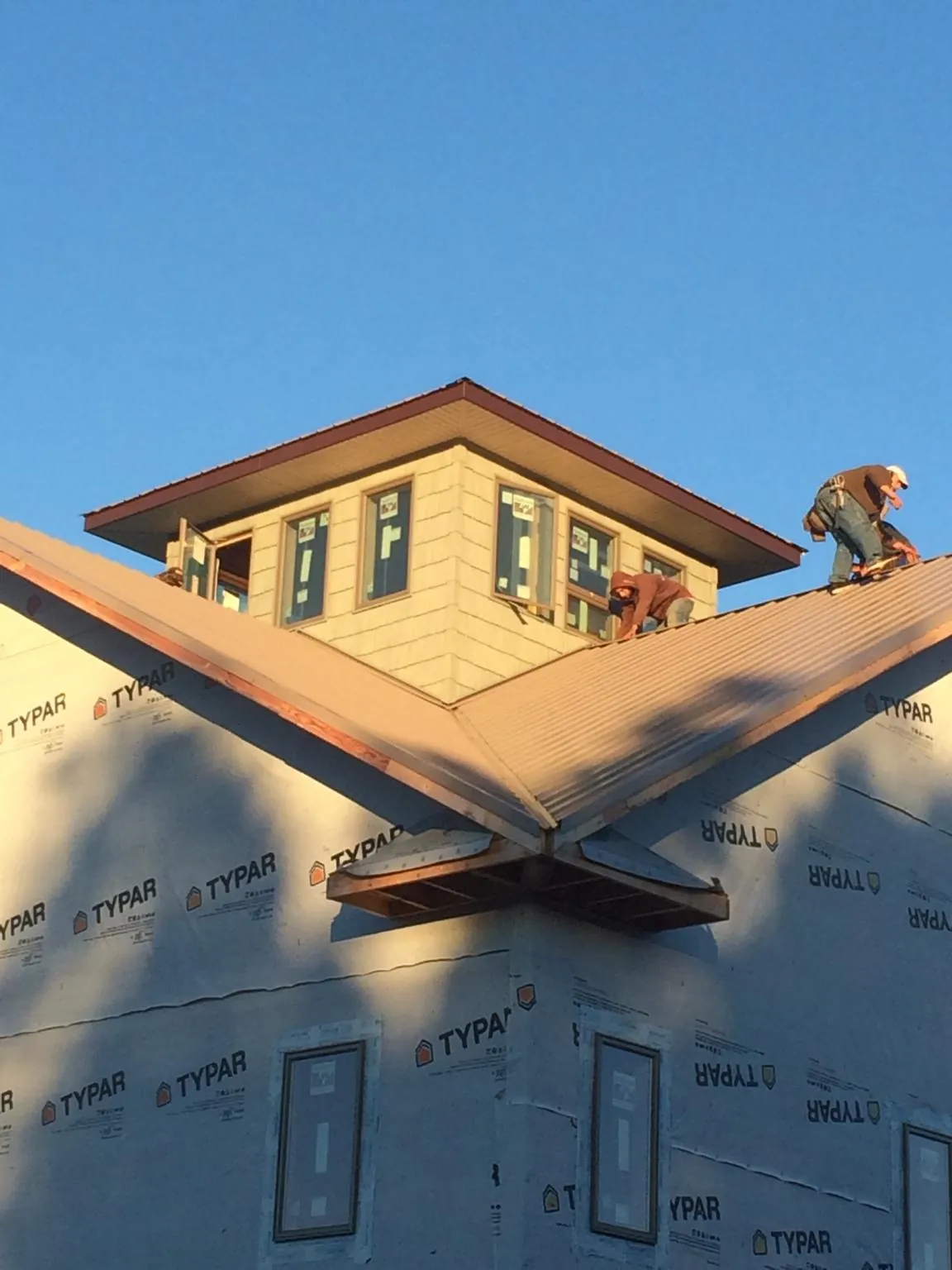 Roofers working around a rooftop cupola on a new metal roof at sunset — Roof Waterproofing in Tamworth by Roofing Brothers